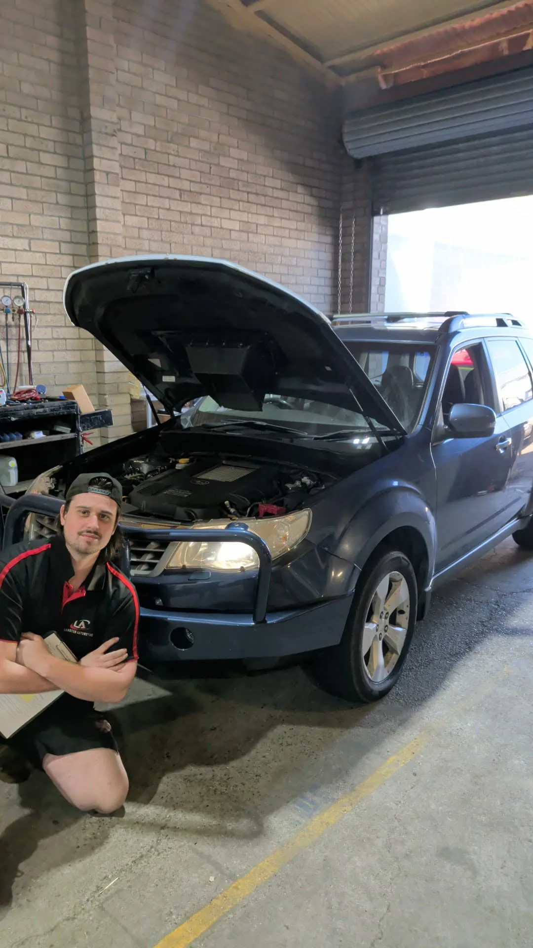 Mechanic in the bay with a Subaru Forester, bonnet up