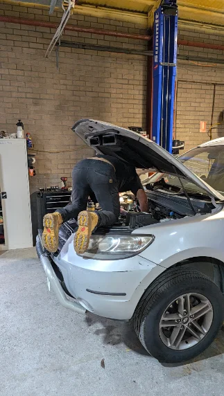 Mechanic leaning into an engine bay at Lambton Automotive